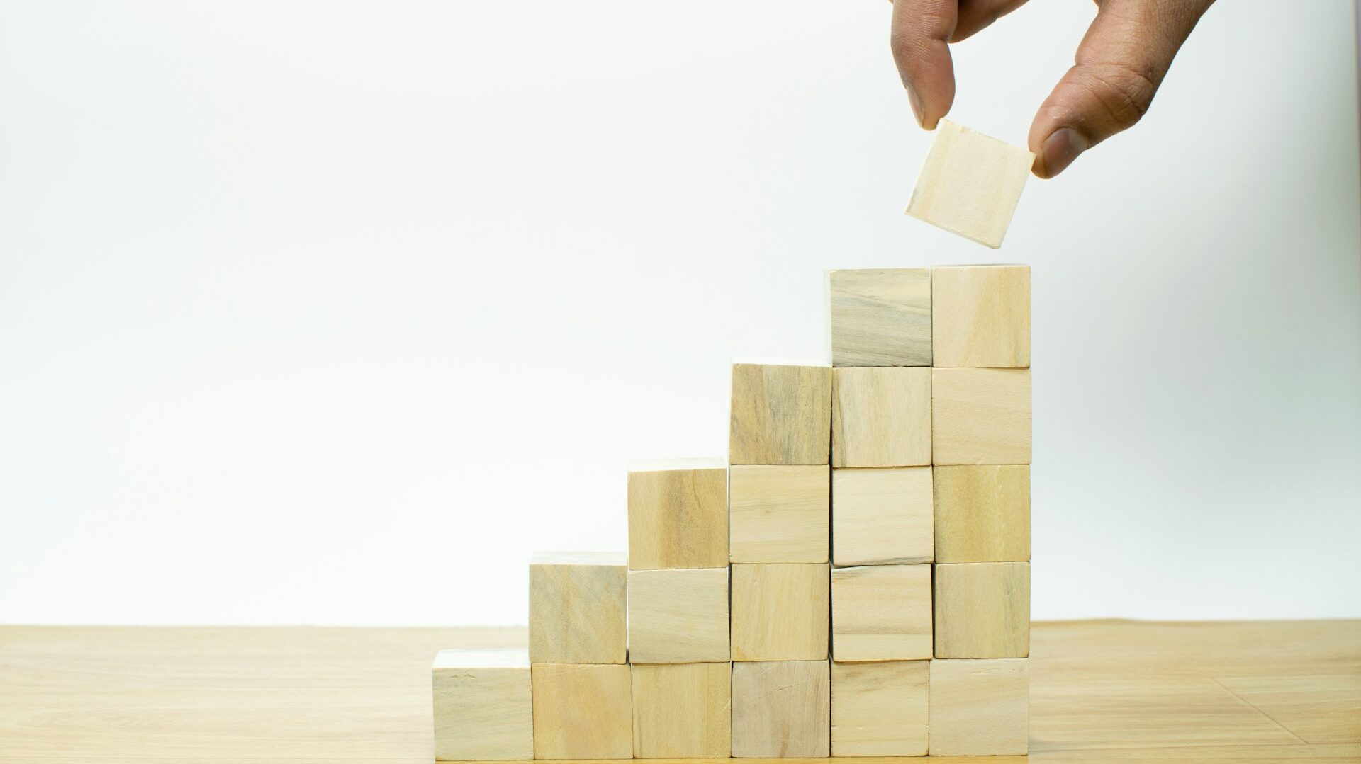 木のブロックを階段状で右方向に積み上げていく手と、積み上げられた木のブロック